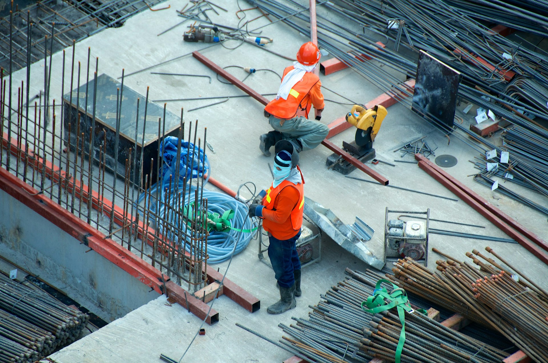 Indian construction site at sunrise — scaffolding, steel rebar, and helmeted workers on an active mid-rise build