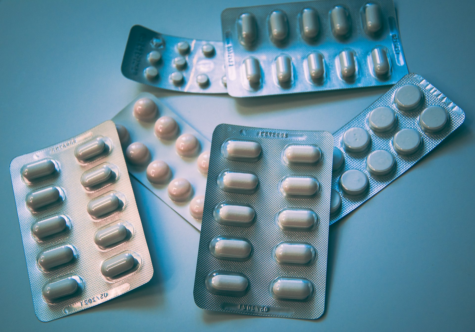 Indian pharmacy retail counter with blister-pack inventory rows and a pharmacist reviewing a prescription